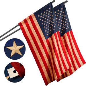 May include: Two American flags with red and white stripes and a blue field of stars. The flags are mounted on dark gray poles. Close-up details show a star and the flag's construction.
