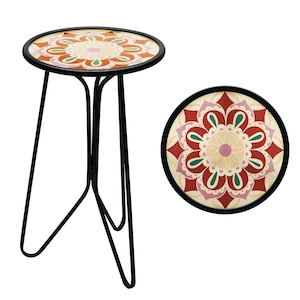 May include: A small, round side table with a black metal frame and a decorative floral top. The tabletop features a mandala design in shades of red, orange, green, and cream. The table has three slender legs.