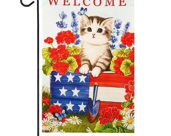 Pode incluir: Uma bandeira de jardim de boas-vindas com um gatinho fofo sentado em um vaso vermelho, branco e azul com flores. A bandeira tem a palavra "WELCOME" impressa nela.