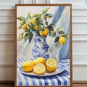 Può includere: Dipinto ad acquerello di limoni e vegetazione in un vaso blu e bianco, con limoni su un piatto e un bicchiere d'acqua. Il dipinto è incorniciato in una cornice di legno e posto su uno sfondo a righe blu e bianche.
