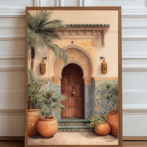 Op de afbeelding: Een ingelijste print met een gewelfde deur met houten deur en ingewikkelde gravures. De scène toont potplanten, sierlijk tegelwerk en een palmboom, allemaal in warme, aardse tinten. Twee gouden lantaarns flankeren de deuropening.