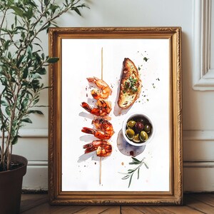 Op de afbeelding: Een ingelijste aquarel schilderij met gegrilde garnalen aan een spies, een sneetje geroosterd brood en een klein bakje olijven. Het kunstwerk staat in een gouden lijst tegen een witte achtergrond. Een takje rozemarijn is ook inbegrepen.