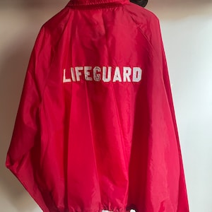 May include: Red lifeguard jacket with a white "LIFEGUARD" embroidered on the back.