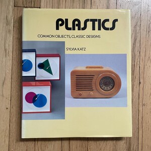 May include: A book titled "PLASTICS" with the subtitle "COMMON OBJECTS, CLASSIC DESIGNS" by Sylvia Katz. The cover features images of geometric shapes and a vintage radio in shades of orange, red, and blue.