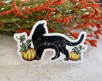 May include: A die-cut sticker featuring a solid black cat silhouette standing among white-outlined pumpkins and two colored yellow-orange pumpkins with green leaves. The design includes a maple leaf detail on the cat's body and a white border.