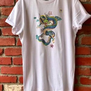 May include: White t-shirt with a colorful dragon graphic and the Japanese character "九" printed on the front.