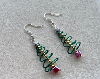 Puede incluir: Un par de pendientes de árbol de Navidad verde y dorado con cuentas rojas y estrellas plateadas.
