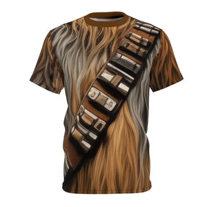 May include: A brown and white t-shirt with a printed image of Chewbacca from Star Wars. The shirt features a brown bandolier with silver buckles.