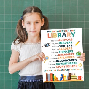 May include: A colorful poster with the text "When you enter this library..." and a list of words describing what people are when they enter a library, including "authors", "readers", "writers", "leaders", "thinkers", "dreamers", "explorers", "researchers", "adventurers", "storytellers". The poster also includes a bookshelf with books and the text "You are the reason why we're here!"