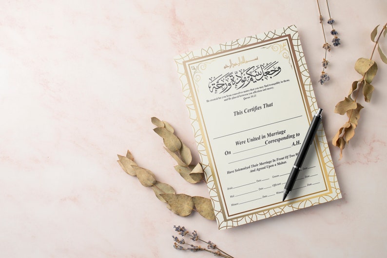 May include: A white and gold Islamic marriage certificate with Arabic calligraphy and a black pen on a pink surface.