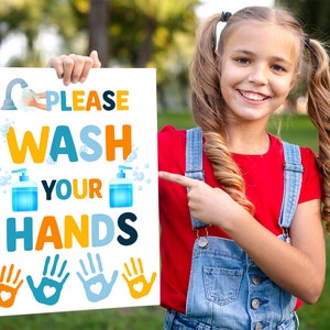 Może przedstawiać: Biały znak z tekstem "PLEASE WASH YOUR HANDS" w kolorowych literach. Znak zawiera ilustracje myjących się rąk, butelek z mydłem i baniek. Młoda dziewczyna trzyma znak i wskazuje na niego.