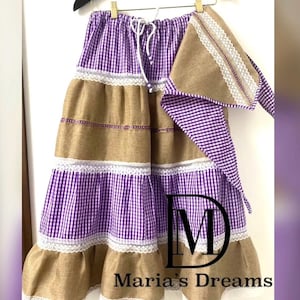 May include: A multi-layered skirt with a purple and white gingham pattern, brown burlap fabric, and white lace trim. The skirt has a matching purple and white gingham scarf with lace trim. The skirt is tied with a white drawstring. The skirt is labeled "Maria's Dreams".