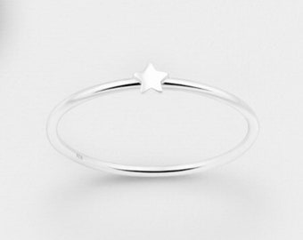 May include: A simple silver ring with a small star design.