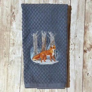 Zorro rojo bordado en un bosque invernal nevado sobre fondo gris pizarra azulado. Toalla de cocina de rizo de algodón con tejido gofrado.
