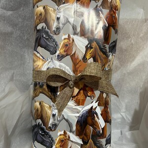 May include: A gift wrapped in brown paper with a brown bow. The paper features a repeating pattern of horses in various colors and poses.