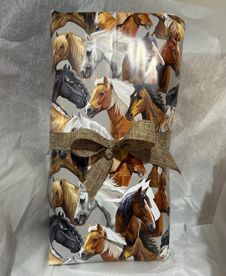 May include: A gift wrapped in brown paper with a brown bow. The paper features a repeating pattern of horses in various colors and poses.