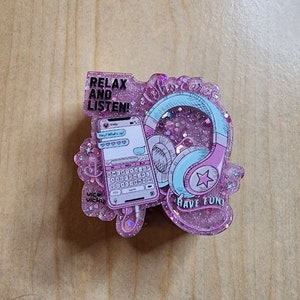 May include: Pink and blue glitter resin charm with a phone, headphones, and the text "Relax and Listen!" and "Who cares, Have Fun!"