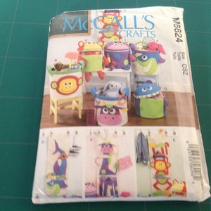 May include: A sewing pattern for making toy storage containers. The pattern includes instructions for making a monkey, a monster, a fish, a cow, and a giraffe. The pattern is from McCall's Crafts and the pattern number is M6624.