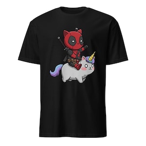 May include: Black t-shirt with a cartoon image of Deadpool riding a unicorn. Deadpool is wearing his signature red and black suit and holding a katana. The unicorn is white with a pink mane and a rainbow horn.