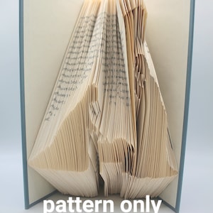 May include: A book with pages folded into a pattern, creating a three-dimensional shape. The book is closed and has a blue cover. The text "pattern only" is printed below the book.