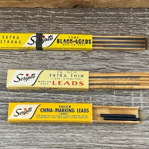 May include: Three yellow and black boxes of Scripto brand lead refills. The top box says "Long Black Leads, Extra Strong, Medium Soft". The middle box says "2 1/4 inch Extra Thin (.036 Diameter) Medium Soft Leads". The bottom box says "Thick China-Marking Leads (Wax) For Marking on Glass, China, Leather, Metal, Cellophane, Film, and Many Other Surfaces".