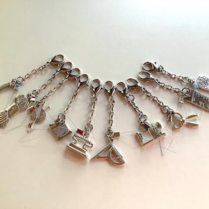 May include: A set of ten silver stitch markers with different charms, including a ball of yarn, a ruler, a sewing machine, and a pair of scissors.