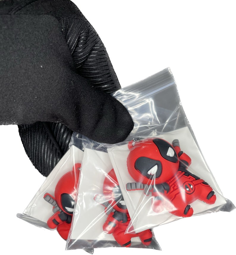 Peut inclure: Trois porte-cl&eacute;s en caoutchouc repr&eacute;sentant le personnage de Deadpool, en rouge et noir, dans des sachets en plastique transparent individuels. Les porte-cl&eacute;s sont en caoutchouc et ont un design 3D.