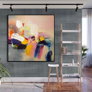 May include: Abstract painting with a colorful, layered design. The painting features shades of pink, yellow, blue, green, and white. The painting is framed in a black frame and is hanging on a gray wall.
