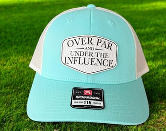 以下が含まれることがあります： ライトブルーとホワイトのトラッカーハットで、ホワイトのパッチには「Over Par and Under the Influence」と書いてあります。ハットはリチャードソン製で、「Low-Pro 115 Trucker」というサイズタグが付いています。