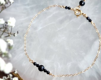 Peut inclure: Un bracelet délicat en chaîne dorée avec des perles d'onyx noir. Le bracelet est doté d'un fermoir à homard.