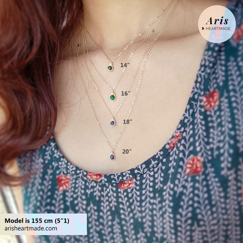 May include: A close-up of four gold necklaces with teardrop pendants in different colors. The necklaces are 14, 16, 18, and 20 inches long. The model is 5'1" tall. The brand name "Aris Heartmade" is visible in the upper right corner.