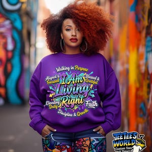 May include: A purple sweatshirt with the text "I Am Living Right" in a colorful design. The sweatshirt also features the phrases "Walking in Purpose," "Aligned & Focused," "Blessed & Grateful," "Elevating Daily," "Discipline & Growth," and "Faith."