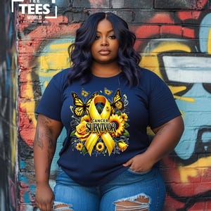 K&ouml;nnte beinhalten: Ein marineblaues T-Shirt mit einem gelben Band, Sonnenblumen und Schmetterlingen. Das Band tr&auml;gt den Schriftzug "Cancer Survivor".