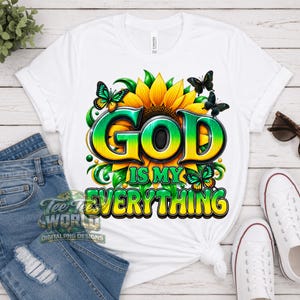 May include: A white short-sleeve t-shirt featuring a large graphic of a yellow sunflower with green and yellow butterflies. The text "GOD IS MY EVERYTHING" is printed in a bold, gradient green and yellow font across the center of the sunflower.