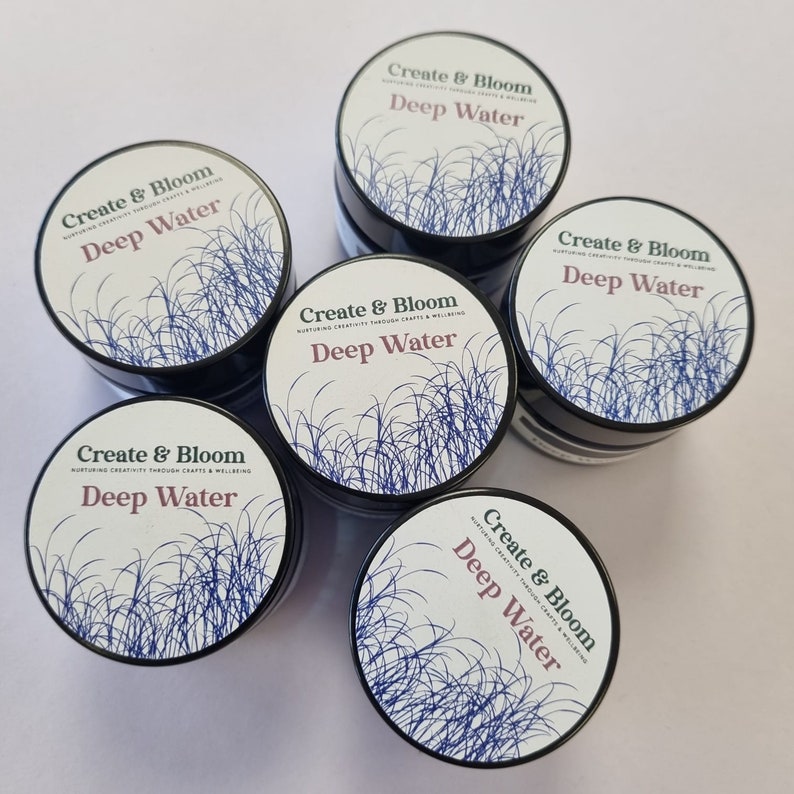 May include: Five small jars of blue and white Deep Water scented wax melt with a leafy design. The jars are labeled "Create & Bloom" and "Deep Water".