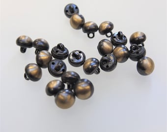 May include: A group of 14 small, round, black and gold buttons. The buttons have two holes and a shiny finish.