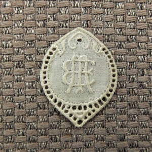 Puede incluir: Doily de encaje blanco con un monograma de las letras "AB" en el centro.