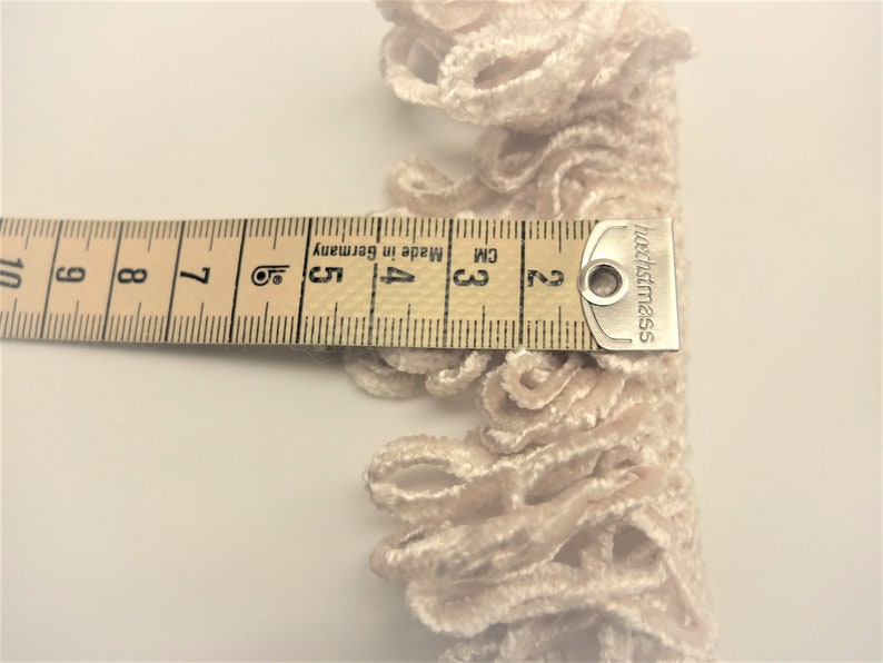 May include: A close-up of a beige velvet trim with a measuring tape showing it is 3 cm wide. The tape reads "hochstmass" and "Made in Germany".