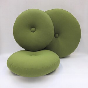May include: Three round green cushions with button tufting. The cushions are made of a soft, textured fabric.
