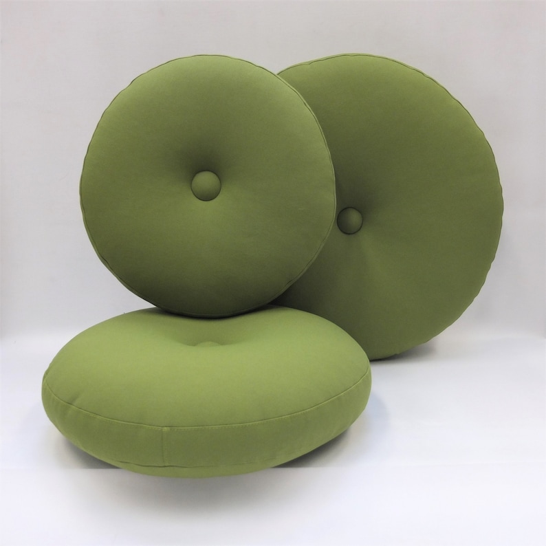 May include: Three round green cushions with button tufting. The cushions are made of a soft, textured fabric.
