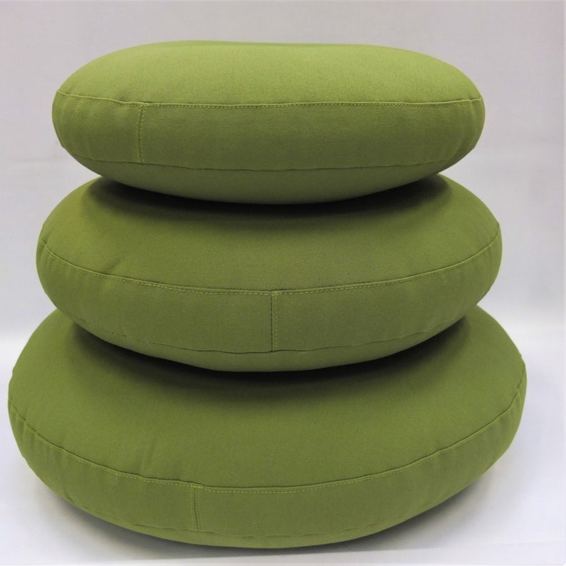 May include: Three round green cushions stacked on top of each other. The cushions are made of a soft, textured fabric.