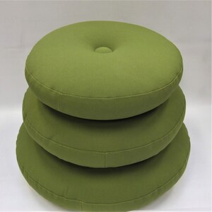 May include: Three round, green cushions stacked on top of each other. The cushions are made of a soft, textured fabric.