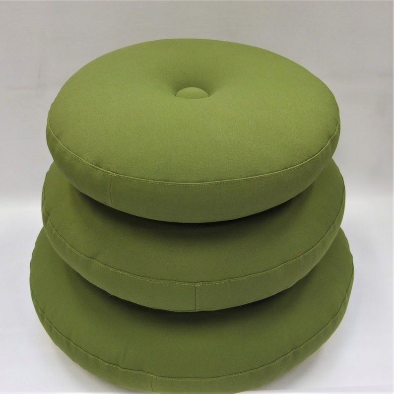 May include: Three round, green cushions stacked on top of each other. The cushions are made of a soft, textured fabric.