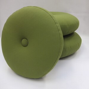 May include: Three round green cushions with a button detail in the center. The cushions are stacked on top of each other.