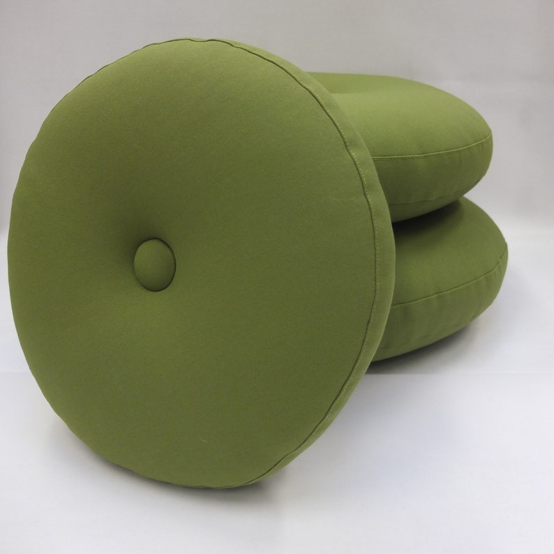 May include: Three round green cushions with a button detail in the center. The cushions are stacked on top of each other.