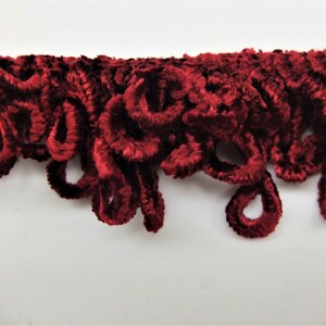 May include: Red velvet trim with a curly, looped design.