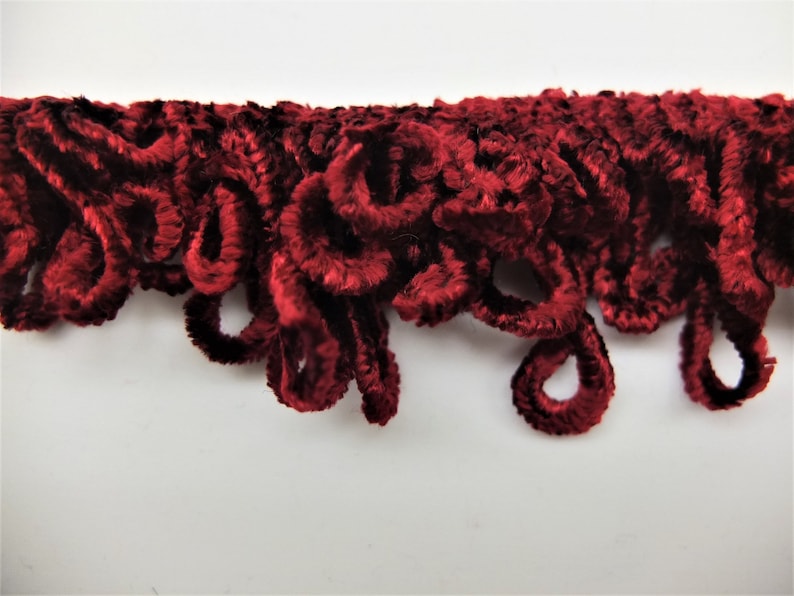 May include: Red velvet trim with a curly, looped design.