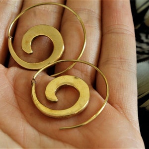 May include: A pair of gold hoop earrings with a spiral design. The earrings are made of metal and have a simple, elegant look.