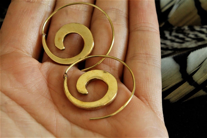 May include: A pair of gold hoop earrings with a spiral design. The earrings are made of metal and have a simple, elegant look.