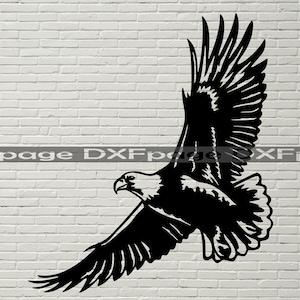 May include: A black silhouette of an eagle in flight with its wings spread wide. The eagle is facing left and has a sharp beak. The background is a white brick wall.